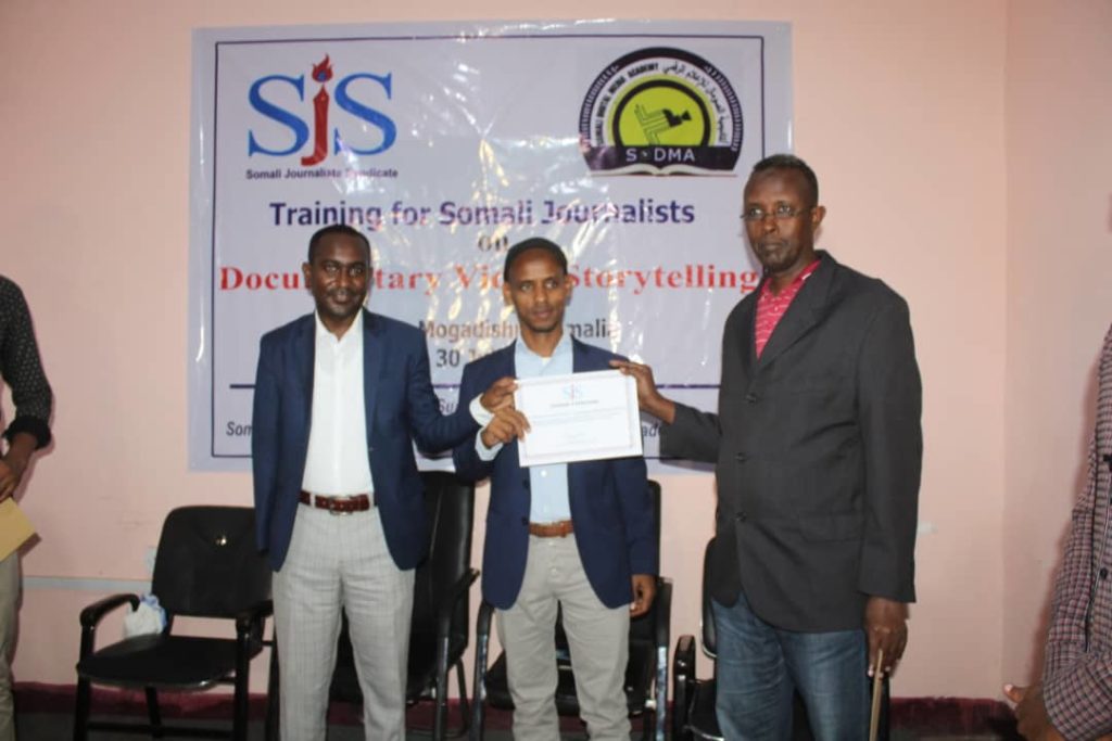 Abdalle Ahmed Mumin (left), the Secretary General of Somali Journalists Syndicate (SJS) wards certificate of appreciation to the director of Somali Digital Media Academy (SODMA), Abdulrahman Yusuf Hassan, on Thursday 8 August 2019 as a two-week course on Documentary Video Storytelling concluded in Mogadishu.