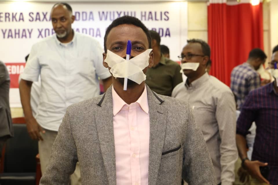 Hanad Ali Guled, the editor of Goobjoog Media Group crosses his mouth with a tape and a pen in protest against the repressive media law.