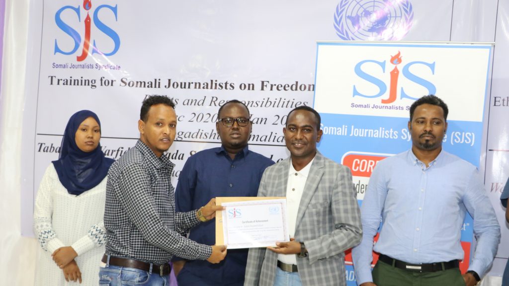 SJS Secretary General, Abdalle Mumin (right centre) hands over a certificate of completion to SOM NEWS TV journalist Salad Mohamed after attending a three-day training on Freedom of Expression supported by UNSOM, Friday 1 January, 2020. | PHOTO/SJS.