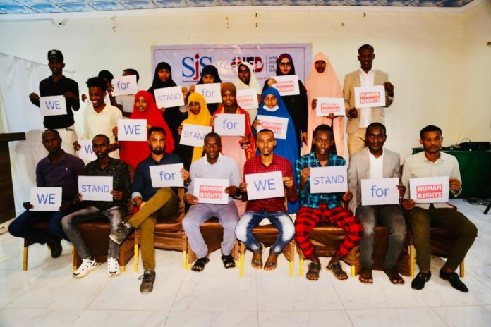 Participants holding posters pledging to 'stand for human rights' pose for a group photo at the end of three-day human rights journalism training in Baidoa on Monday, 14 February, 2022.