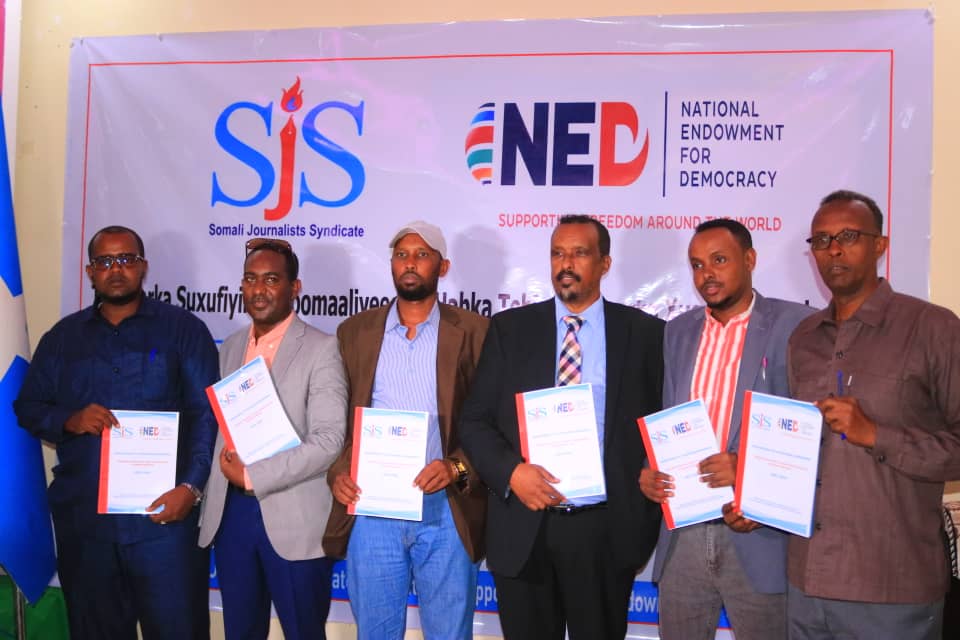 Galmudug Minister of Information, Ahmed Falagle (centre), followed by Adado District Administration representative, Abdirahman Moalim, a representative from Galmudug Ministry of Information join SJS Secretary-General, Abdalle Mumin and trainer Abdirahman Hassan for a group photo to officiate the human rights journalism training in Galmudug, Thursday 9 June, 2022. |PHOTO/SJS. 