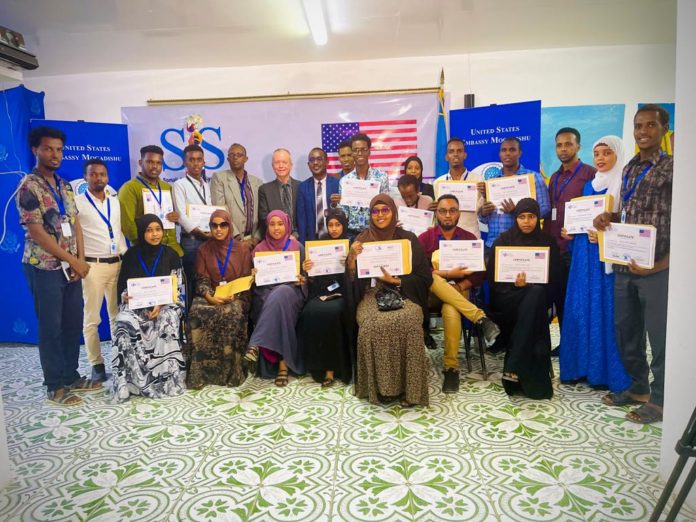 Training participants pose for a group photo alongside the SJS Secretary-General, Abdalle Ahmed Mumin and the U.S Ambassador, Larry André in Mogadishu, on Wednesday 27 July, 2022.