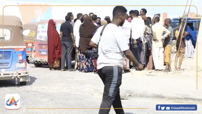 Journalist walks behind members of the public speaking to other journalists at School Polizia cemetery in Mogadishu on Tuesday, June 11, 2024. | PHOTO/ Arlaadi Media Network.